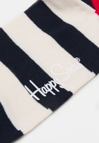 Striped sock in navy and cream with a red accent. Features a soft texture and displays the "Happy Socks" logo in white.