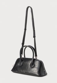 Borsa a mano in pelle nera con doppi manici e tracolla rimovibile. Presenta una forma arrotondata, dettagli con zip argentati e una superficie liscia.