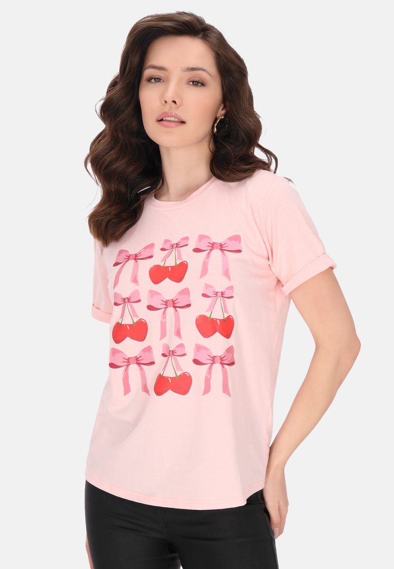Tricou din bumbac roz, cu un model repetat de cireșe roșii și fundițe roz. Mâneci scurte și o croială lejeră pentru un confort sporit.