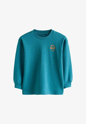 Sini-sinine dressipluus pikade varrukatega, valguspingiga kaeluses ja elastsete mansettidega. Rinnal on väike oranž kolju ja kõrvaklappide disain.