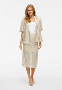 Pärlbeströdd tvådelad outfit bestående av en kortärmad blazer och en figurnära midikjol i guldtoner, som skapar en texturerad, reflekterande yta.