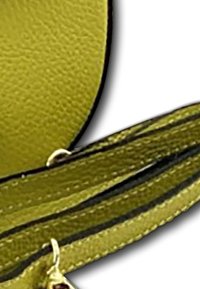 Geel leren materiaal met een gestructureerde afwerking, voorzien van een donkere accentstreep en een gouden hardware detail op het bevestigingspunt.