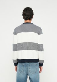 Pulover din tricot cu dungi orizontale în nuanțe de bleumarin, alb și gri. Guler, manșete și tiv cu nervuri. Textură moale, croi lejer.