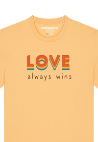 Geel katoenen T-shirt met een meerkleurige afbeelding waarop in vette letters "LOVE" staat, met daaronder in een kleinere lettertype "always wins".