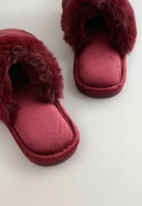 Bordeaux tæpper med pelsfor, blød tekstur, åben tå-design og en polstret indersål. Firkantet form med flad sål.