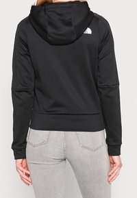 Sudadera negra hecha de un tejido suave y elástico, que cuenta con capucha, mangas largas y un ajuste ceñido en la cintura. Diseño simple sin patrones visibles.