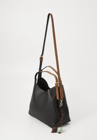 Sac à épaule en cuir noir avec une finition texturée, doté de sangles réglables marron et d'un pompon décoratif avec des accents verts et marron.