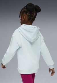 Ljusblå huvtröja med mjuk textur, ribbade ärmar och en avslappnad passform, kombinerad med rosa leggings, sedd bakifrån.