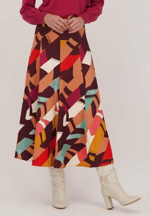 Jupe midi colorée et à motifs, présentant des designs abstraits dans des teintes de rouge, brun et bleu-vert, fabriquée en tissu lisse avec une forme évasée.