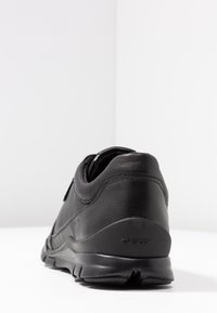 Sneaker in pelle nera con un design elegante, caratterizzato da una finitura testurizzata e una suola ammortizzata. Marchio Geox visibile sul tallone.