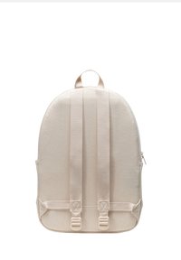Beige canvas backpack with padded back, adjustable shoulder straps, and top handle. Features a zipper closure and reinforced hardware accents.