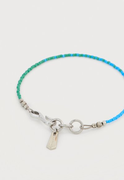 Βραχιόλι με χάντρες, εναλλασσόμενες πράσινες και μπλε μικρές χάντρες, ασημένιο κούμπωμα, στρογγυλό δαχτυλίδι και μία μικρή ορθογώνια μεταλλική ταμπελίτσα.