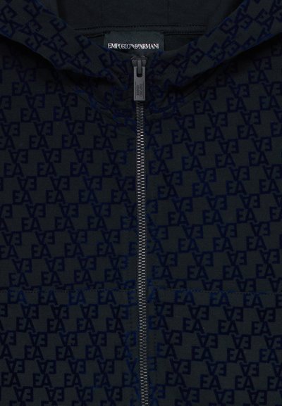 Čierna mikina Emporio Armani s opakujúcim sa vzorom loga "EA", so zipsom vpredu a viditeľnou značkovou nálepkou vo vnútri goliera.