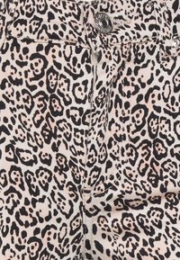 Tecido com padrão de leopardo em bege e preto, com um corte clássico de ganga; possui um botão prateado e detalhes de costura.