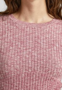 Maglione lavorato a maglia in un leggero rosa e bianco mélange, con una trama a coste e scollo tondo, attillato in vita.