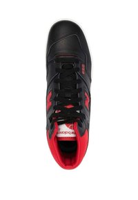 Schwarzer und roter New Balance 650 Sneaker mit schwarzen Schnürsenkeln, rotem Innenfutter und sichtbar angebrachtem Logo an der Seite und der Zunge, von oben gezeigt.