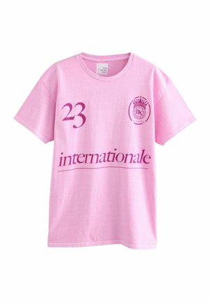 Rózsaszín pamut póló, kerek nyakkal. Jellemzője egy nagy lila "23" és alatta az "internationale" felirat. Bal mellen kör alakú logó található.