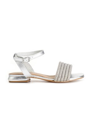 Silver sandal with an ankle strap, featuring a textured upper band of pleats and a low block heel. Smooth metallic finish throughout.