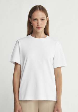 Witte katoenen t-shirt met korte mouwen en een ronde halslijn, met een relaxte pasvorm en een zachte textuur. Minimalistisch ontwerp, geen patronen of accenten.