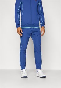 Trackset in Königsblau mit hellblauen Akzenten. Die Jacke hat einen Reißverschluss und Rippbündchen; die Hose hat eine schmale Passform.