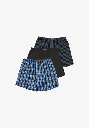 Männlicher Torso trägt blau-schwarz karierte Boxershorts mit elastischem Bund und sichtbarem Markenlabel.