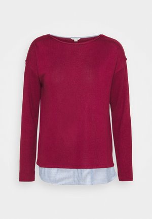 Top de manga larga color burdeos superpuesto sobre el dobladillo de una camisa a rayas azul y blanca, cuello redondo, ajuste holgado, estilo casual.