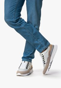 Herren-Sneaker aus einer Mischung von grauen, weißen und beigen Materialien. Sie verfügen über eine strukturierte Sohle und kontrastierende Schnürsenkel sowie eine gepolsterte Knöchelpartie.
