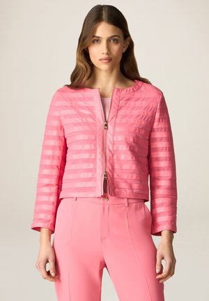 Giacca fucsia trapuntata aderente con righe orizzontali, collo rotondo e chiusura con zip dorata. Abbinata a pantaloni fucsia coordinati.