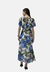 Vestido maxi floral con mangas cortas, con flores azules y verdes sobre un fondo blanco, cintura ajustada y un detalle de corte en la espalda.
