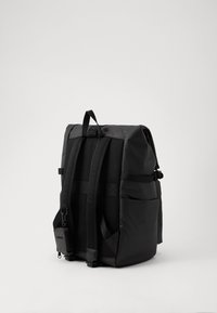 Crna naprtnjača izrađena od izdržljive, teksturirane tkanine s podstavljenim trakama, prednjim džepom i prilagodljivim bočnim kopčama. Čist, minimalistički dizajn.