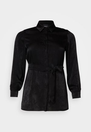 Svart langermet bluse laget av glatt stoff, med knappelukking foran, krage og en knytebelte i midjen for en figursydd silhuett.