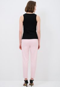 Zwarte mouwloze top gecombineerd met lichtroze gep tailored broek, met een gladde textuur en een slim fit. Zwarte hoge hakken maken de look compleet.