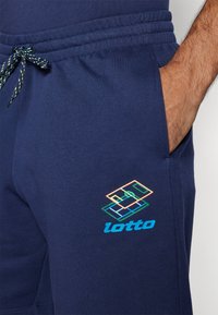 Morski kratki hlače z vrvico v pasu, stranskimi žepi in večbarvnim grafičnim logotipom Lotto na spodnjem levem delu.