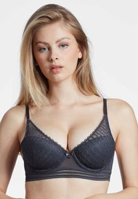 Bralette en dentelle gris foncé avec des bonnets triangulaires, des bretelles réglables et une bande élastique décorative. Présente un motif floral en dentelle et un accent en nœud central.