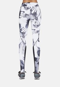Legginsy z wysokim stanem w białym kolorze z czarnym kwiatowym wzorem, z kontrastowymi czarnymi panelami bocznymi, dopasowanym krojem i teksturowaną tkaniną.