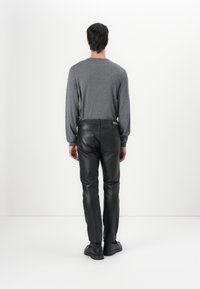 Sivý sveter s dlhým rukávom a okrúhlym výstrihom, skombinovaný so slim-fit čiernymi koženými nohavicami. Jednoduchý dizajn s hladkou textúrou.