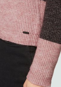 Gebreide trui in lichtroze en donkergrijs met geribbelde textuur. Voorzien van een klein zwart etiket dat in de zoom is genaaid.