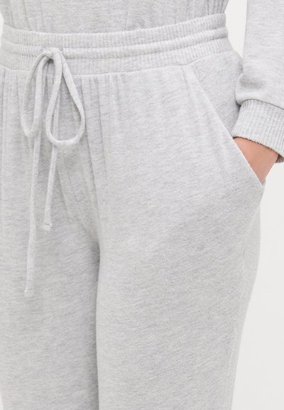 Pantalon de survêtement gris en tissu doux, doté d'une taille côtelée, d'un cordon de serrage et de poches latérales. Texture lisse avec une coupe décontractée.