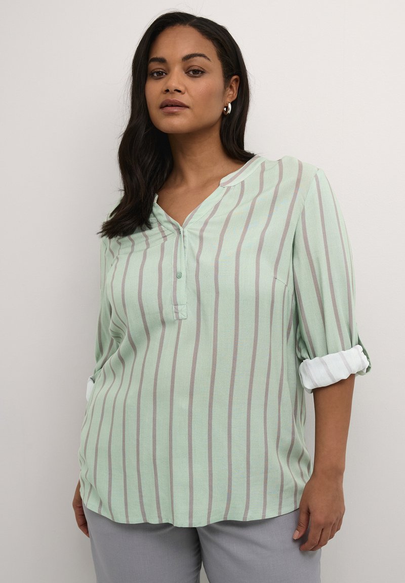 Mint green button-up shirt with vertical white and gray stripes, collarless design, and rolled sleeves, crafted from lightweight fabric.