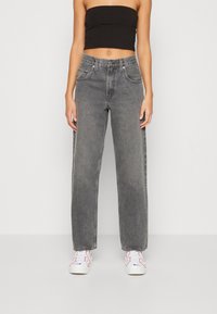 Höga, vida jeans i urtvättad grå denim med femfickorsdesign och metallknapp. Matchat med vita sneakers.