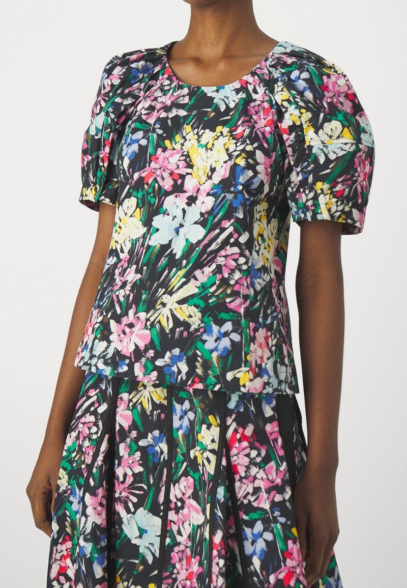 Top floreale a maniche corte con sfondo nero, caratterizzato da vivaci fiori rosa, blu e gialli, e maniche a sbuffo gatherate per un tocco di texture in più.