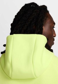Sudadera con capucha de un brillante tejido amarillo neón; presenta un acabado suave y texturizado con una capucha relajada y un mínimo detalle de costura.