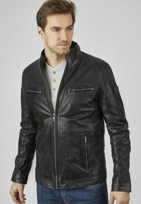 Schwarze Lederjacke mit Reißverschluss vorne, Stehkragen, zwei Brusttaschen und seitlichen Reißverschlusstaschen. Strukturiertes Finish und taillierte Passform.