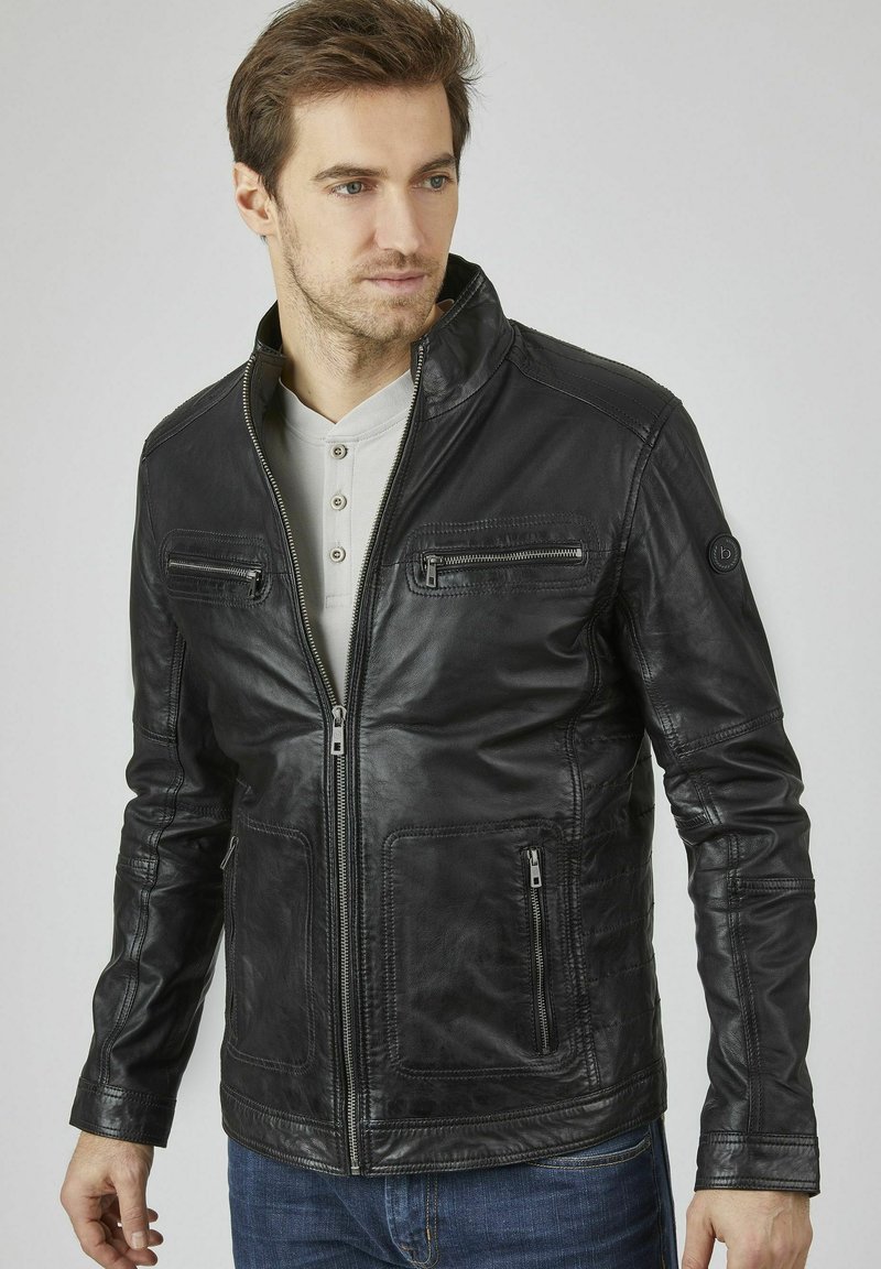 Schwarze Lederjacke mit Reißverschluss vorne, Stehkragen, zwei Brusttaschen und seitlichen Reißverschlusstaschen. Strukturiertes Finish und taillierte Passform.