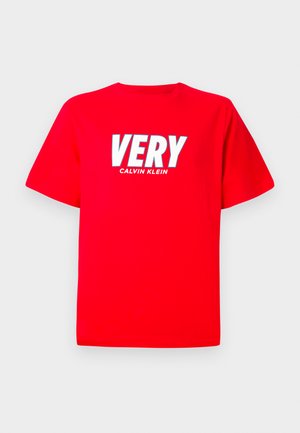 Červené tričko s krátkym rukávom, na ktorom je veľkými bielymi písmenami nápis "VERY" a pod ním menším bielym textom "CALVIN KLEIN".