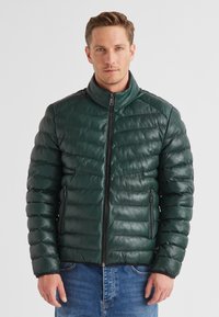 Grüne Leder-Pufferjacke mit hohem Kragen, horizontalem Steppmuster, Vorderreißverschluss und zwei seitlichen Reißverschlusstaschen.