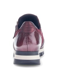 Bordeauxfarbener Sportschuh mit einem glänzenden Obermaterial aus Leder und Wildleder, ausgestattet mit einer abgerundeten Zehenpartie und einer gepolsterten Sohle mit einem weißen und schwarzen Streifen.