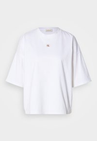 Hvit bomulls t-skjorte med kort erme, løs passform, og en liten rød og gull logo i midten. Enkel og fortsatt design.