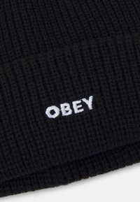 Mustra musta kudum, millel on soonikkoes; esiküljel on valge tikkitud "OBEY" logo.
