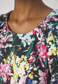 Abito a stampa floreale con sfondo nero e fiori brillanti rosa, gialli e verdi. Tessuto liscio con scollatura rotonda e maniche a sbuffo.